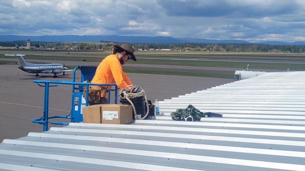 Man on edge of roof roof performing roof maintenance