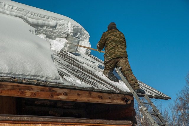 A man removing snow from a roof for Can you fix a roof in the Montana winter? 