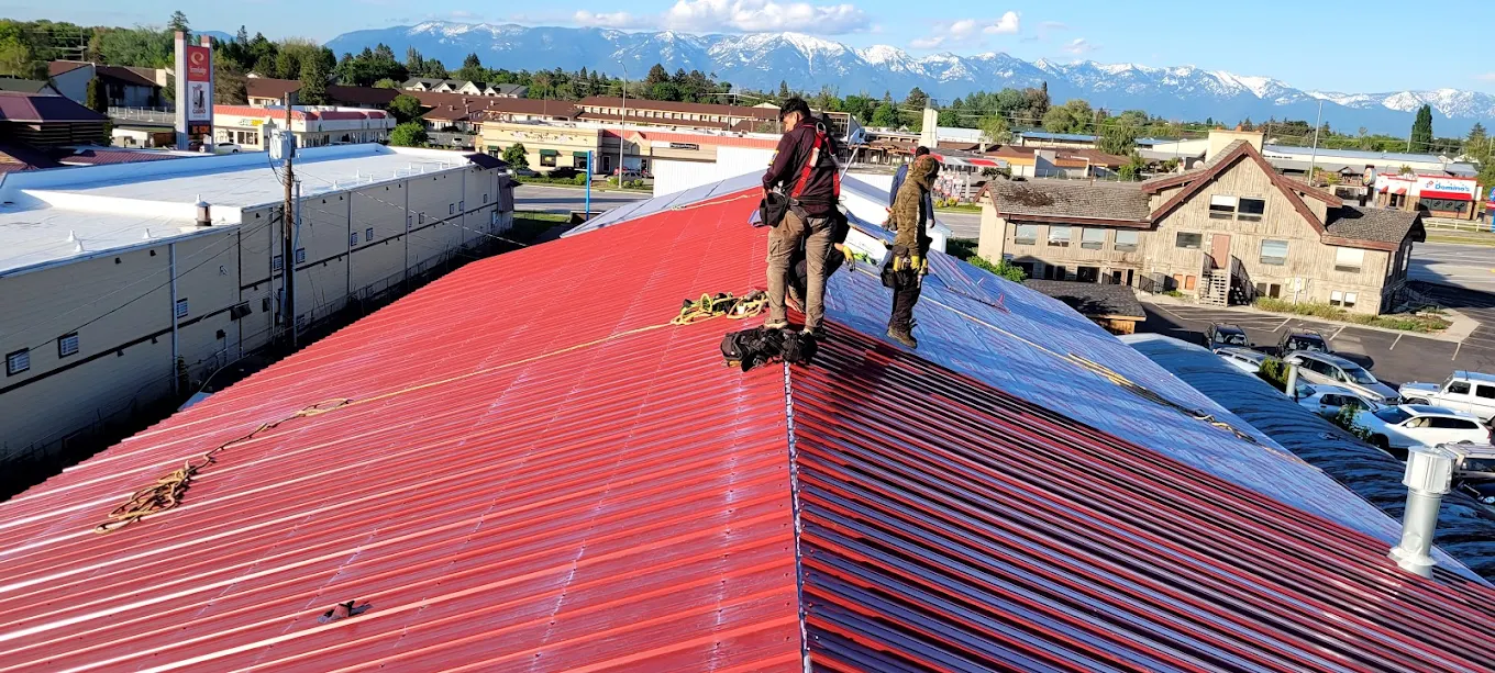 Roofers replacing metal roof on a commercial building